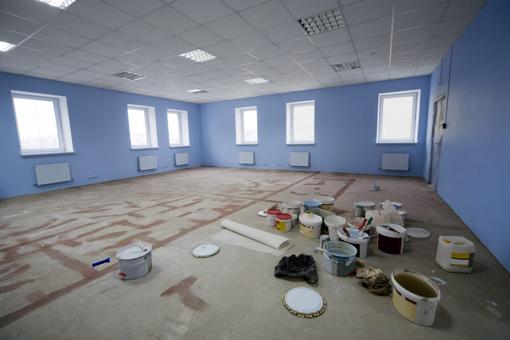 interior painting job with paint buckets and tools on the ground