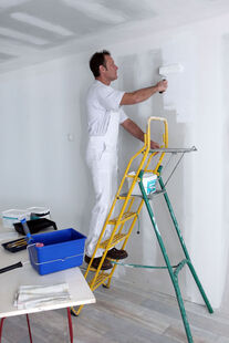 Interior Painting on a ladder with a paint roller painting the wall
