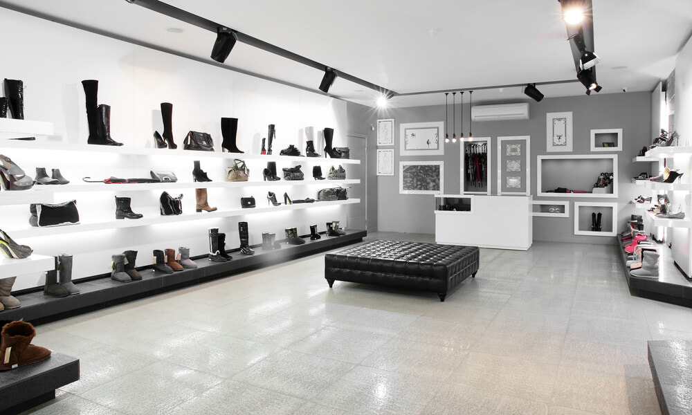a freshly painted shoe store with a grey feature wall and white shelfs done by our shop painters